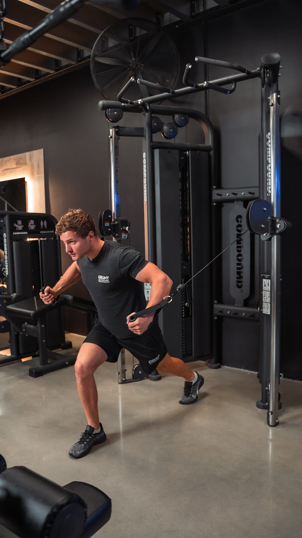 Functional trainer corner with mirror wall in a boutique gym by Compound Fitness