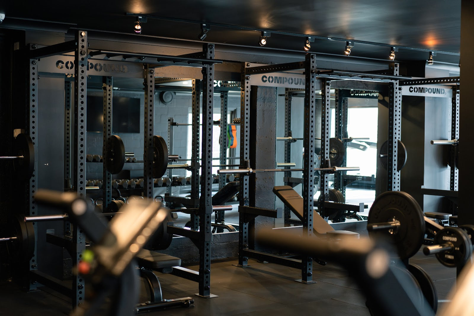 Row of squat racks and benches in a boutique gym by Compound Fitness