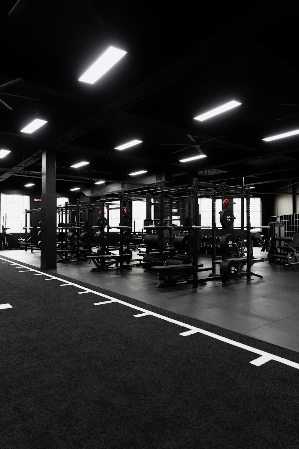 Strength floor with rig line and turf sprint lane in a boutique gym by Compound Fitness
