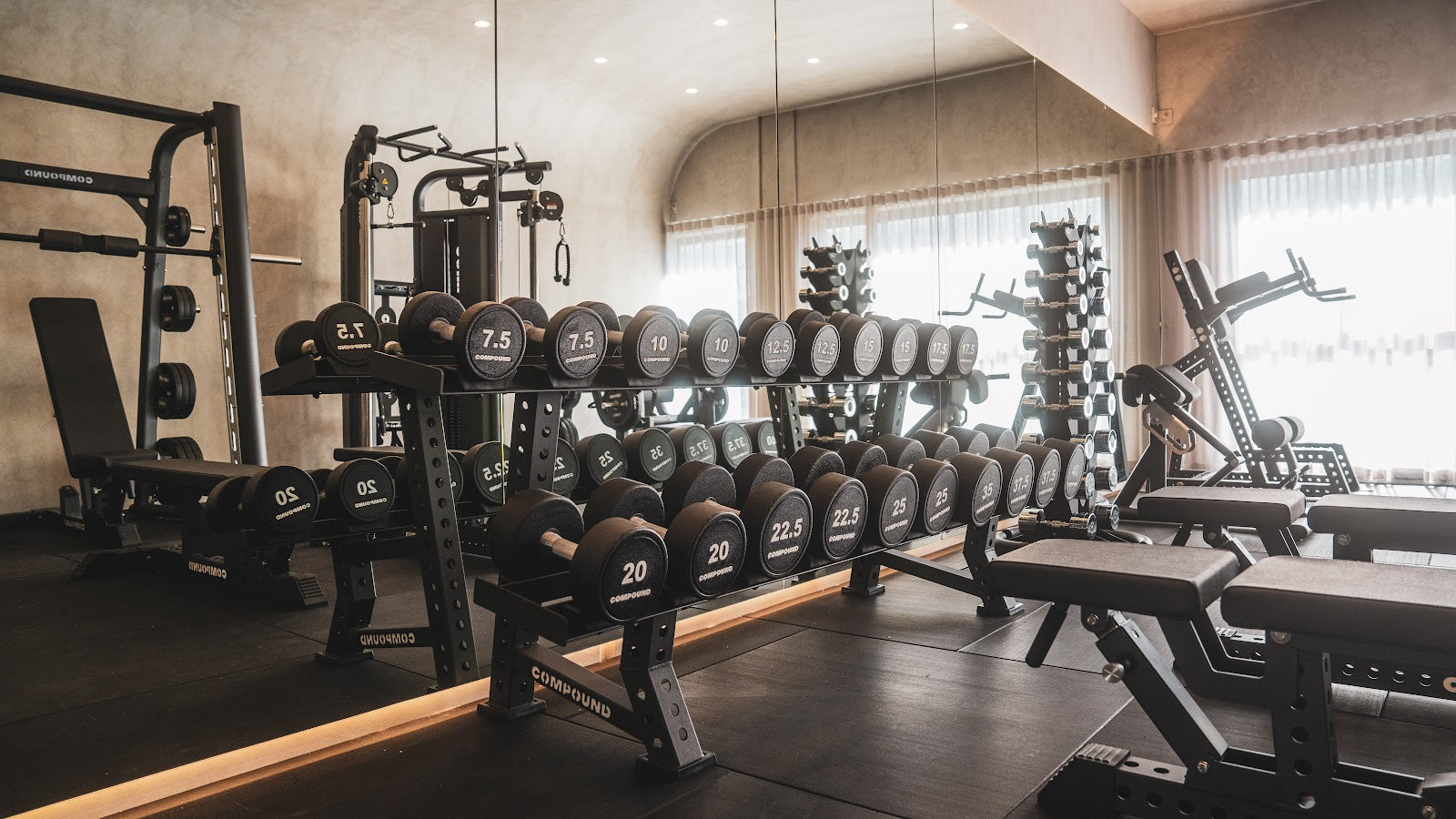 Dumbbell racks, benches and cable machine in a boutique studio by Compound Fitness