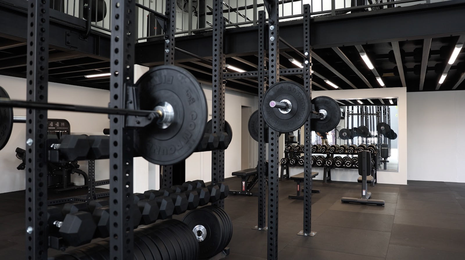 Two-level industrial boutique gym with rig and free weights by Compound Fitness