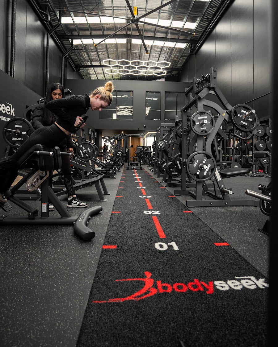 Members training beside the branded turf runway in a 24/7 gym by Compound Fitness
