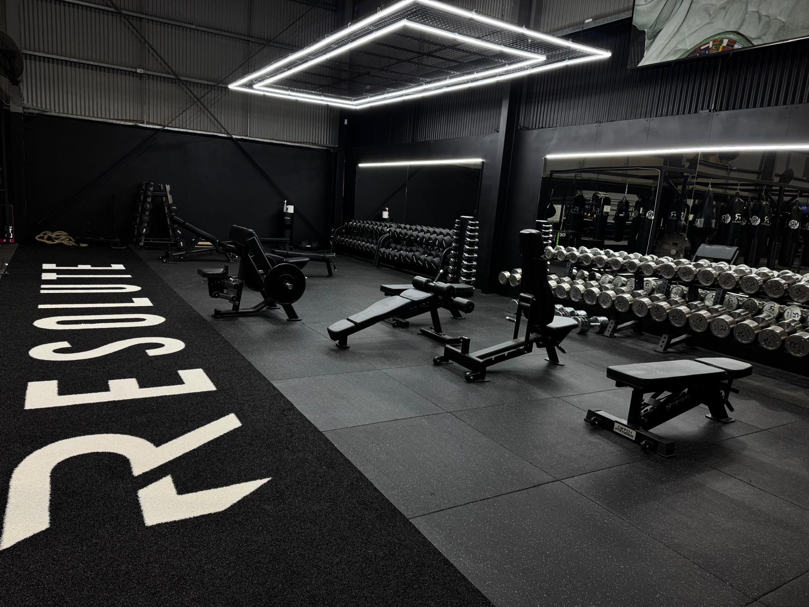 Free weights floor with custom turf, benches and dumbbell wall in a 24/7 gym by Compound Fitness