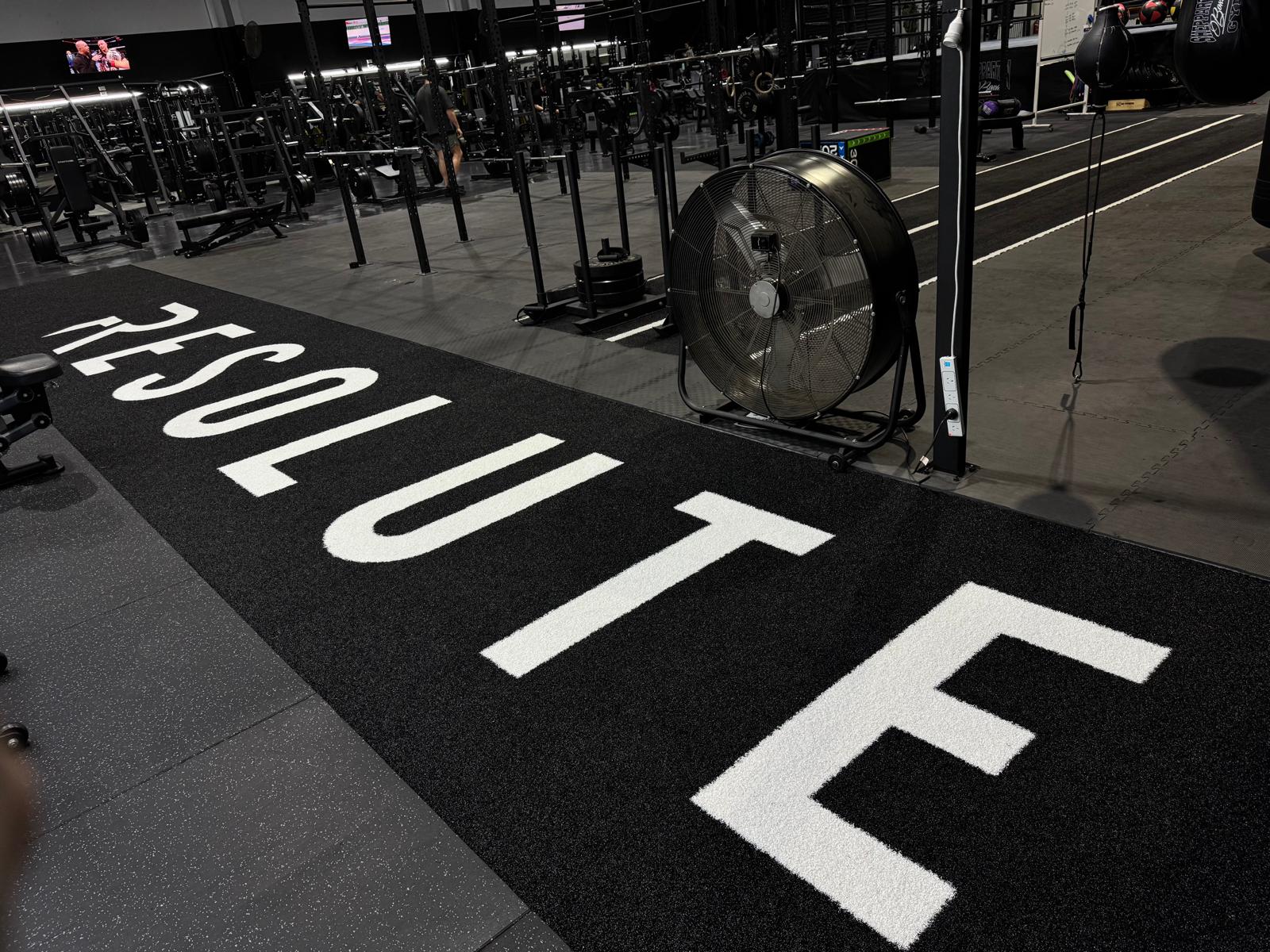 Custom branded turf with racks and rigs across a 24/7 gym floor by Compound Fitness