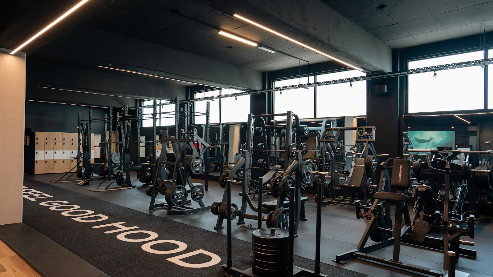 Full room view of a 24/7 gym fitout with branded turf and machine zone by Compound Fitness
